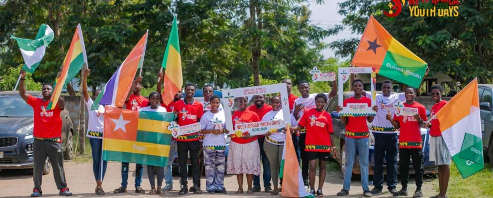 Gruppe junger Menschen bei den „West Africa Youth Days Accra 2026“, die im Freien gemeinsam westafrikanische Flaggen und Veranstaltungsschilder präsentieren.