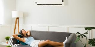 Eine Frau liegt unter der Klimaanlage auf dem Sofa